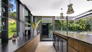 A modern kitchen with dark wood cabinets, a glass backsplash, and pendant lighting. - Tarentaal Kloof Villa in Higgovale. (Cape Town)