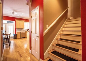 A staircase with a handrail, a kitchen area with wooden cabinets, and a dining area with a table and chairs.