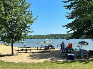 Ein Picknickplatz am Seeufer mit Picknicktischen und Bänken, umgeben von Bäumen.
