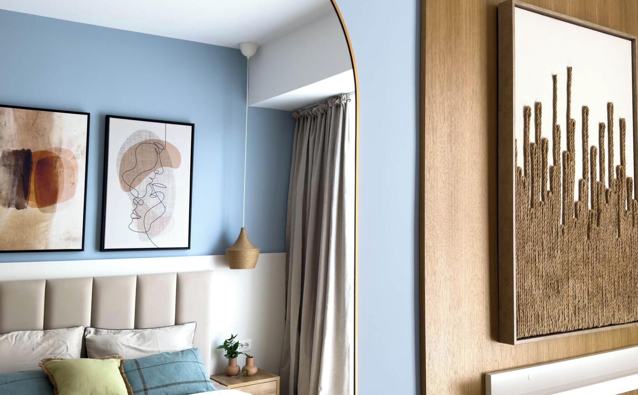 A bedroom with a bed, a headboard, a wall-mounted artwork, and a window with curtains.