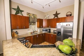 A kitchen with wooden cabinets, a stainless steel refrigerator, a microwave, and a sink. - Spacious 3BR 3BA Home Private Pool Walk to Beach (Rincon)