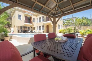 Un espace extérieur abrité avec des sièges, une piscine, des chaises longues et une table avec un plateau.