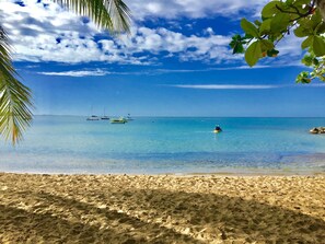 A beach with clear turquoise water, a sandy shore, and several boats in the distance. - Spacious 5BR 4.5BA Home Private Pool Walk to Beach (Rincon)