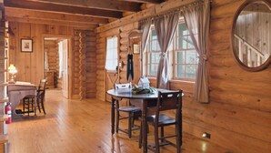 A wooden cabin interior with a dining table, chairs, a small house model, and a fire extinguisher. - Townsend Charm: River View Historic Log Cabin! (Townsend)