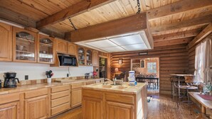 Una cocina de estilo cabaña con armarios de madera, una isla central y un comedor con mesa y sillas.