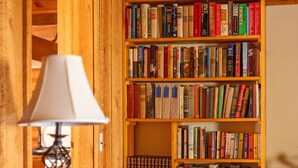 Una estantería de madera llena de libros, una lámpara y un aparador de madera.