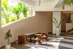 Un interior moderno con un banco, dos macetas de cobre y un ventanal que da a zonas verdes.