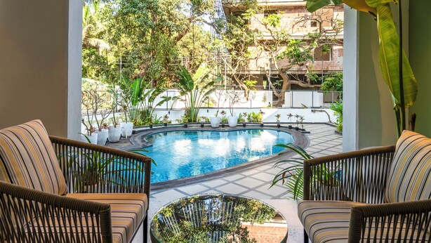 A pool area with wicker furniture and potted plants. - Staymaster Solintra 2BHK C401 (Verem)