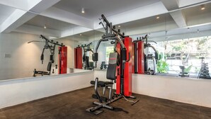 A gym with exercise equipment, a large mirror, and a view of greenery outside. - Staymaster Solintra 2BHK C401 (Verem)