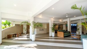 A spacious lobby with a checkered floor, potted plants, a reception desk, and a green sofa. - Staymaster Solintra 2BHK C401 (Verem)