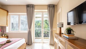 A bedroom with a bed, curtains, a TV, a dresser, and a window with a view. - Staymaster Solintra 2BHK C401 (Verem)