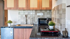 A modern kitchen with wooden cabinets, a microwave, a sink, and a refrigerator. - Staymaster Solintra 2BHK C401 (Verem)