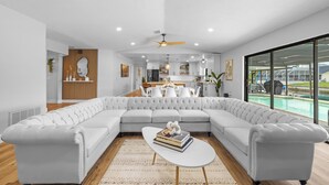 Een moderne woonkamer met een ruime modulaire bank, een witte salontafel en een plafondventilator.