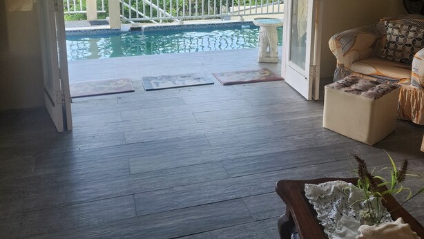 An open living area with a view of a pool and a balcony. - Beautiful 3-Bedroom Home with Pool in Signal Hill (Signal Hill)