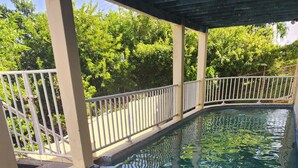 A clear swimming pool with tiled steps leading into it, surrounded by a white fence and greenery. - Beautiful 3-Bedroom Home with Pool in Signal Hill (Signal Hill)