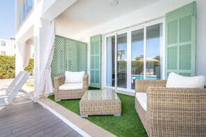 Un balcon agrémenté de meubles en osier, une piscine et une vue sur la mer.