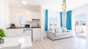 A modern apartment with a kitchen, dining area, and living room with a sofa and curtains. - 1-Bedroom Apartment 'G' with Sofa Bed, Shared Pool, Wi-Fi & Air Conditioning (Felanitx)