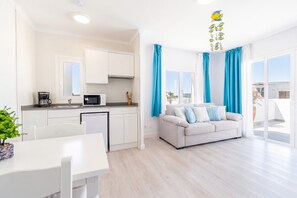 A modern apartment with a kitchen, dining area, and living room with a sofa and curtains. - 1-Bedroom Apartment 'G' with Sofa Bed, Shared Pool, Wi-Fi & Air Conditioning (Felanitx)