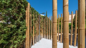 A pathway lined with tall bamboo poles, surrounded by dense greenery. - 1-Bedroom Apartment 'G' with Sofa Bed, Shared Pool, Wi-Fi & Air Conditioning (Felanitx)