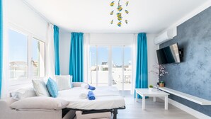 A modern hotel room with a bed, a sofa, a TV, and a balcony with a view. - 1-Bedroom Apartment 'G' with Sofa Bed, Shared Pool, Wi-Fi & Air Conditioning (Felanitx)