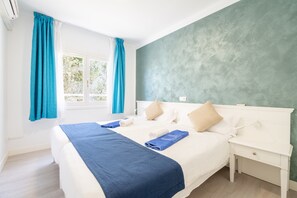 Ein Schlafzimmer mit einem Bett, einem Nachttisch, einem Fenster mit Vorhängen und einer grünen Wand.
