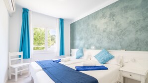 A hotel room with a bed, a chair, a nightstand, and a window with curtains. - 2-Bedroom Apartment 'F' with Shared Pool, Wi-Fi, and Air Conditioning (Felanitx)