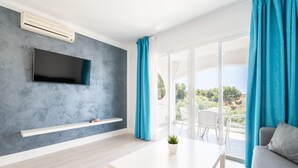 A modern living room with a flat-screen TV, a white table, and a sofa. - 2-Bedroom Apartment 'F' with Shared Pool, Wi-Fi, and Air Conditioning (Felanitx)