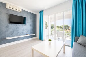 Een moderne woonkamer met een flatscreen televisie, een witte tafel en een bank.