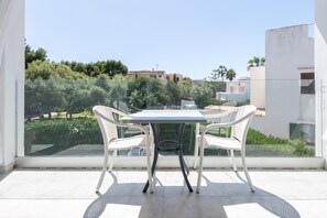 Ein Balkon mit Tisch und Stühlen, der einen Blick auf eine Wohngegend mit Bäumen und Gebäuden bietet.