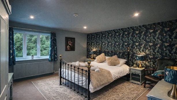 Une chambre à coucher avec un lit, une table de chevet, une chaise, une fenêtre et un radiateur.