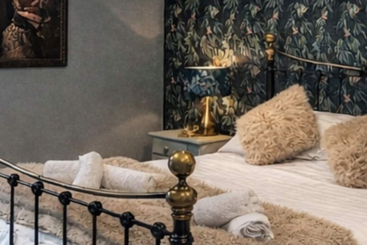 A bedroom with a bed, a nightstand, a lamp, and a painting on the wall.