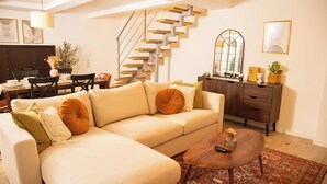 A living room with a sofa, coffee table, and a staircase. - Cozy apartment with garden near Cologne (Frechen)