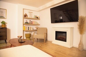 A living room with a fireplace, a television, a bookshelf, and a chair. - Cozy apartment with garden near Cologne (Frechen)