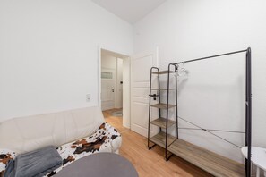 A room with a white sofa, a small round table, and a metal shelving unit with shoes. - Apartment 'Neustadt Kiez' with Wi-Fi (Dresden)