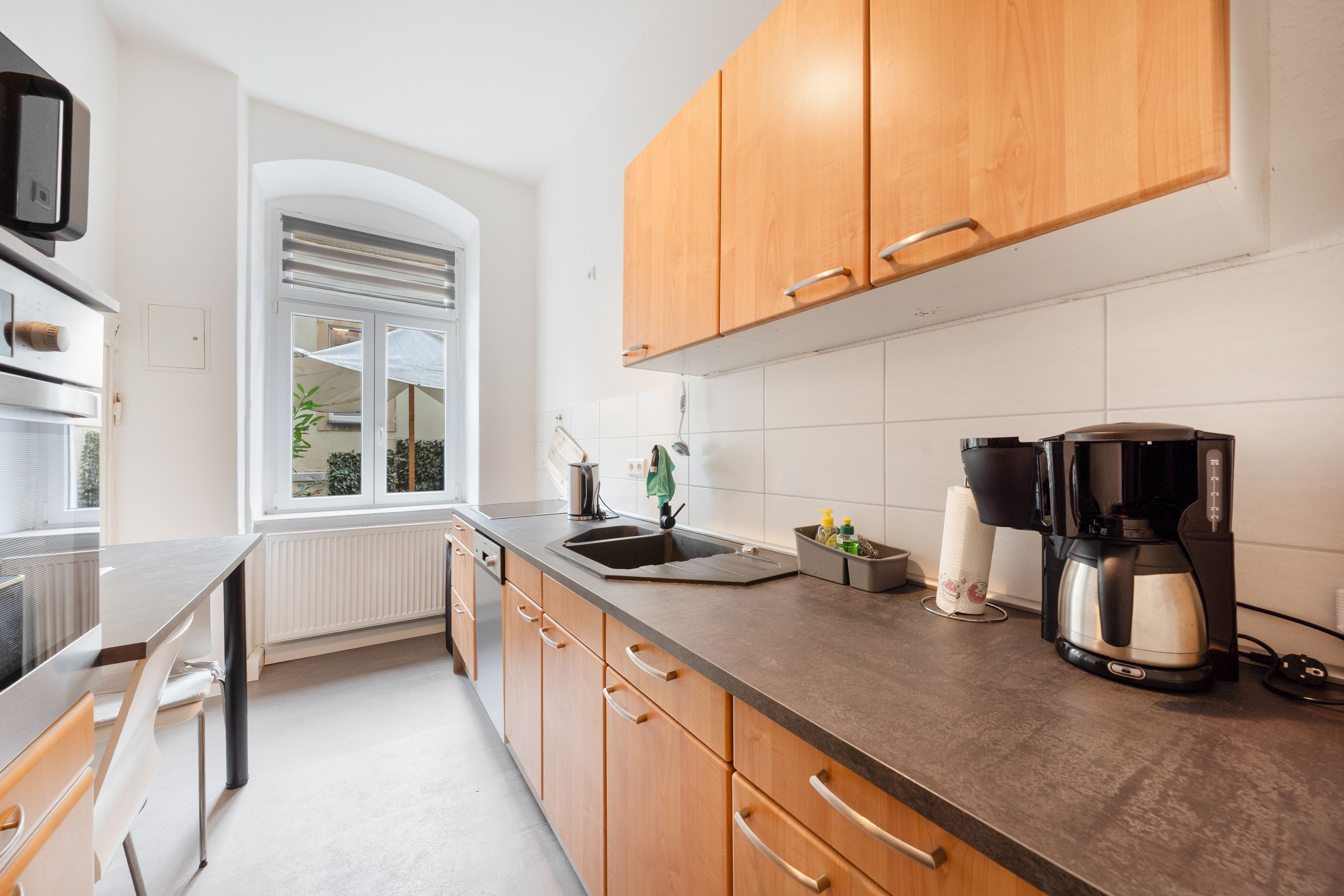 A modern kitchen with wooden cabinets, a stainless steel sink, and a coffee maker.