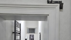 A narrow hallway leading to a bathroom with a toilet, a small window, and a towel rack.