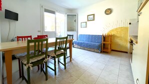 A dining area with a table, chairs, a sofa, and a kitchen area. - Charming Family Flat Near the Beach (San Michele al Tagliamento)