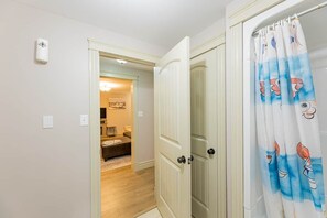 Un pasillo con una puerta que da a una habitación con piso de madera y pared de color claro.