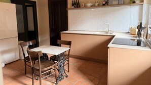 Una cocina compacta con una mesa de comedor, sillas, un refrigerador, un fregadero y una encimera con diversos utensilios de cocina.