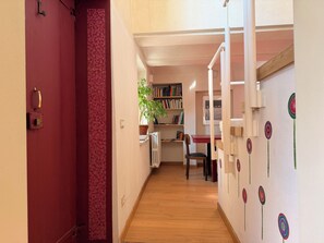 A hallway with a red door, a bookshelf, a radiator, and a chair. - Kiki's - A spacious house with a garden in the Langhe. (Castagnole delle Lanze)