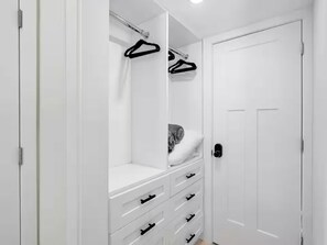 A white closet with hanging space, drawers, and a door. - Seaside Resort 202: Stunning beachfront, heated pool (Fort Myers Beach)