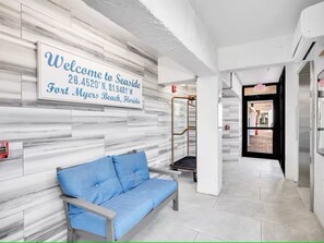 Ein Empfangsbereich mit einer Willkommensanzeige, einem blauen Sofa und einem Aufzug.