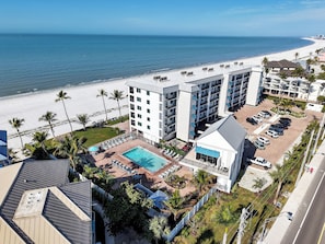 A hotel with a swimming pool, beach view, and parking area. - Oceanfront Condo 210 | Heated Pool + Gulf Views (Fort Myers Beach)