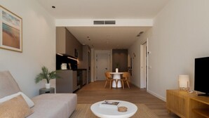 En moderne stue med sofa, sofabord, TV-møbel og et spiseområde i baggrunden.