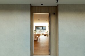 A hallway leading to a dining area with a wooden floor, a table, and chairs. - Premium Apartment, City View, King + Twin (Sitges)