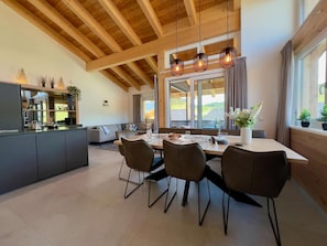 Eine moderne Küche mit Essbereich, Holzbalkendecke und großen Fenstern.