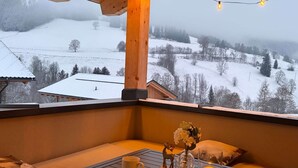 Un balcon accueillant avec vue sur un paysage enneigé, un livre intitulé « Maîtrisez votre état d’esprit » et deux bougies posées sur une table.