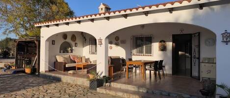 A building with a patio area, a dining table, and a sofa.