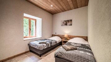 Een slaapkamer met twee bedden, een raam, een houten plafond en een aan de muur bevestigd schilderij.
