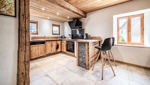 Una cocina con armarios de madera, una isla de piedra y una campana extractora negra.